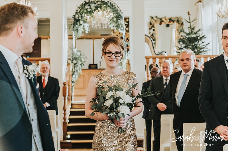 bridesmaid in a gold dress walking down the aisle