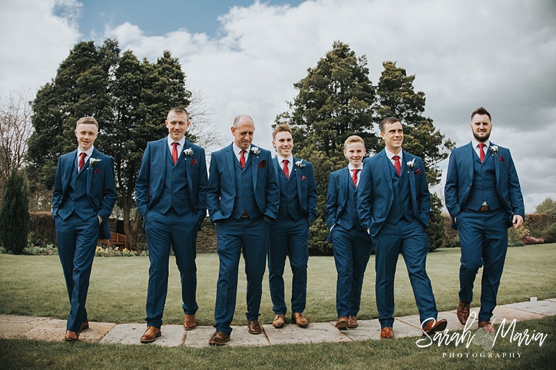 candid shot of all the grooms party walking towards the camera wearing blue suits and red ties