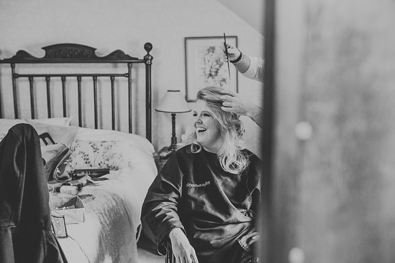 bride on her wedding day laughing whilst having her hair styled