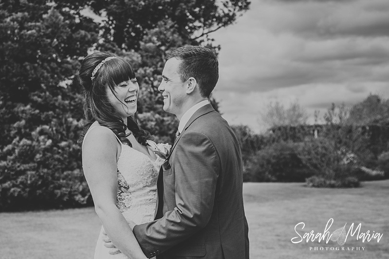natural black and white portrait of a bride and groom. the bride is laughing