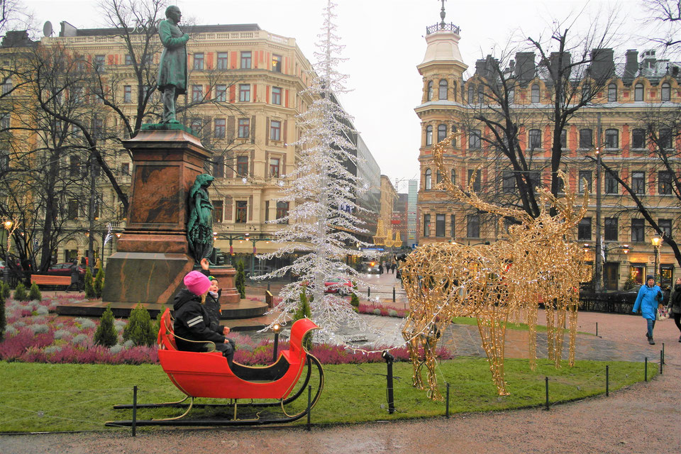 slitta con renne di luci in piazza ad Helsinki e bambini che giocano