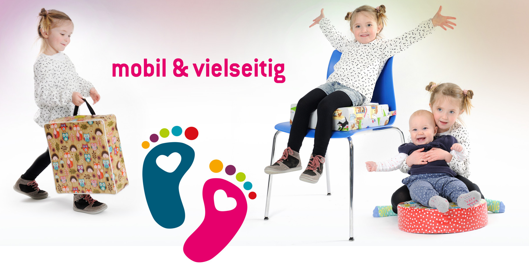 Ein Kind streckt die Arme freudig in die Höhe, weil es auf optimaler Höhe am Tisch mit seiner Sitzerhöhung sitzt