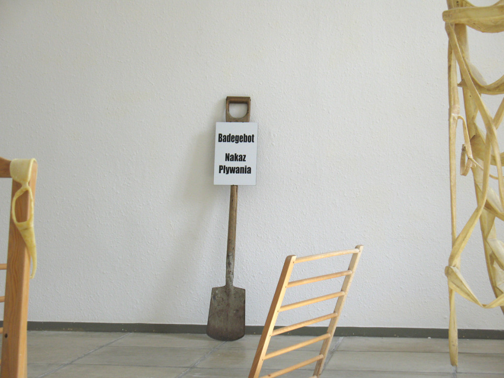 (mixed media: latex, pieces of a cot bed, street sign "swimming commandment", etc.)