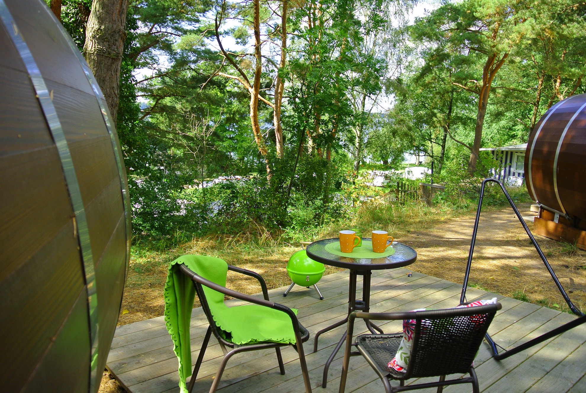 Jedes Fass hat eine eigene Holzterrasse mit Gartentisch, zwei Stühlen, einer Hängematte im Gestell und einer großen wetterfesten Outdoor-Truhe.