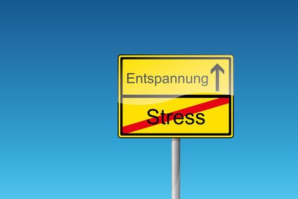 Ein zweigeteiltes gelbes Verkehrsschild vor blauem Himmel: Im unteren Teil steht das Wort Stress. Es ist rot durchgestrichen. Im oberen Teil steht Entspannung. Daneben weist ein Pfeil nach oben.