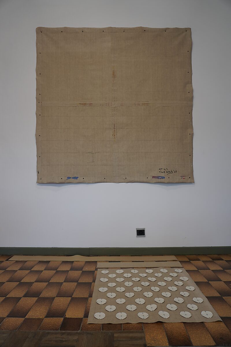 Back side of the linen canvas showing its structure, traces of paint, and the imprint of the flag composition; edges with staples remain visible.