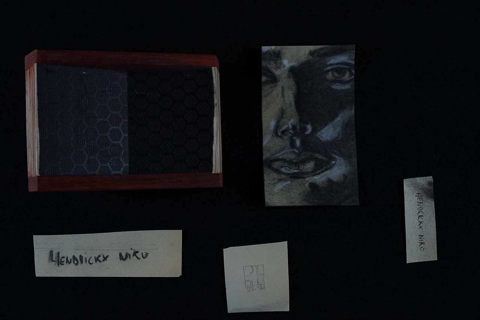 Benoemens-waardvlinders — Naming–Value Butterflies — proces tekening: studie zelfportret 3 PHIKO (1993) — doos, portretfragment en losse papieren labels liggen naast elkaar op een zwarte achtergrond.