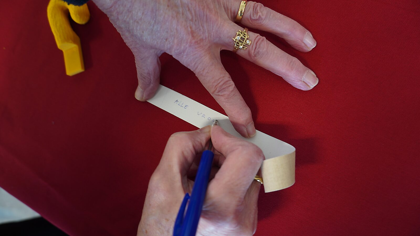 Sfincterman No.0.0 — action videostill: text is written with a pen on the paper strip, stretched beneath the hand.