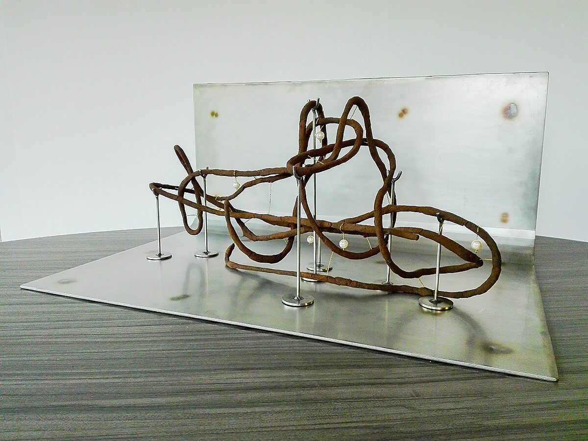 Shipbuilding — final installation of the sculpture on a metal plate with a transparent panel as background.