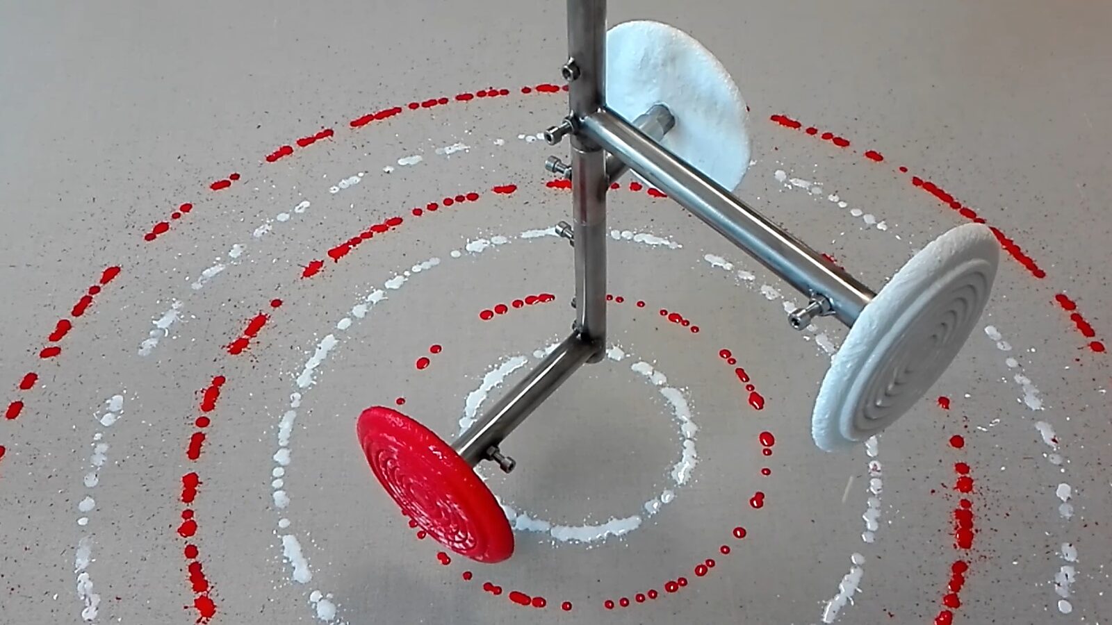 Melting Targets No. 3 — video still of several rotating ice targets spreading red and white drops in concentric circles around the stand.