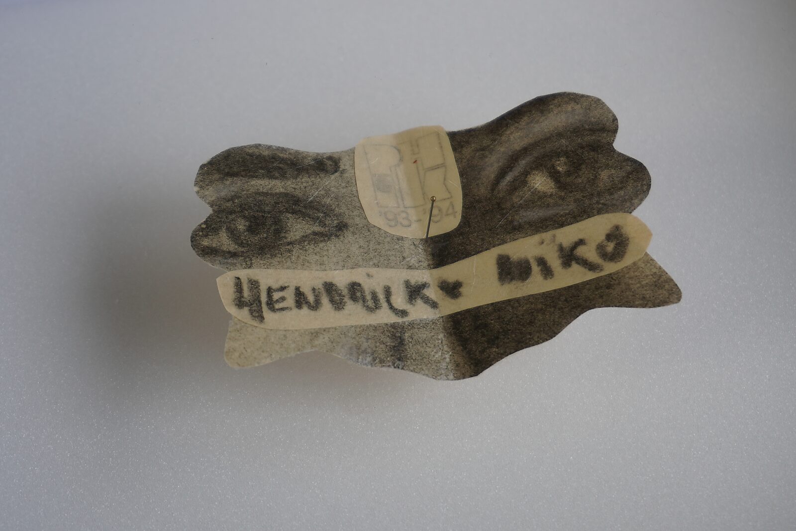 Benoemens-waardvlinders — Naming–Value Butterflies — proces tekening: studie zelfportret 2 PHIKO (1993), Gevangen (2025) — vlindervormig stukje papier met een fragment van twee ogen en een strook met de naam “Hendrickx Niko”.