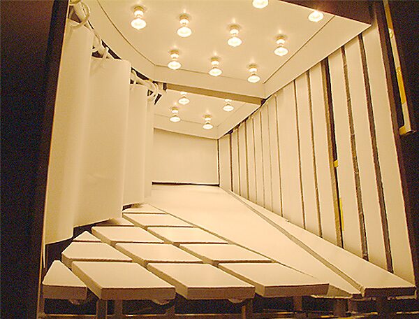 Constructie met blauw — detailfoto van het podium met ingeschakelde verlichting, waarbij het interieur verschijnt als een theatrale ruimte binnen de ontwikkeling van de installatie.