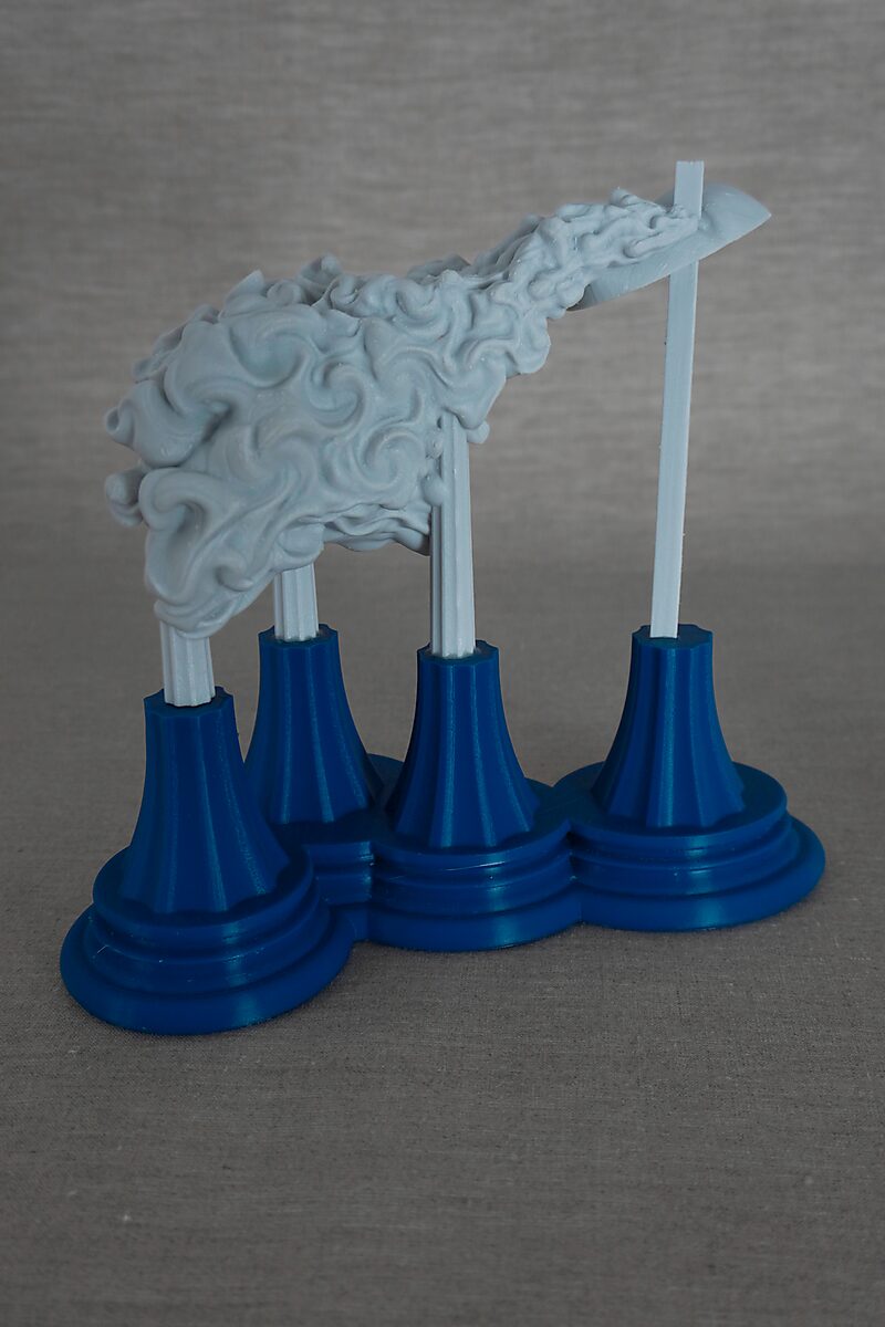 De zuilen van Ovidius — Byblis — zijaanzicht van een langgerekte sculptuur met vloeiende, wolkachtige vormen rustend op witte zuilen met blauwe sokkels.