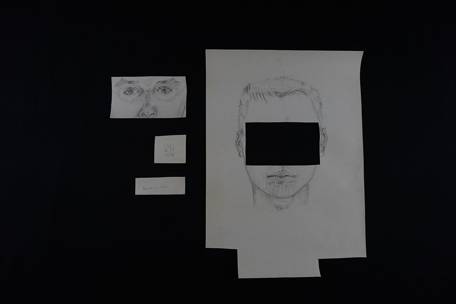 Naming–Value Butterflies — process drawing: study self-portrait 1 PHIKO (1993) — the drawing parts lie separated on the table: a strip with eyes, a small stamp and a name label next to the cut self-portrait.