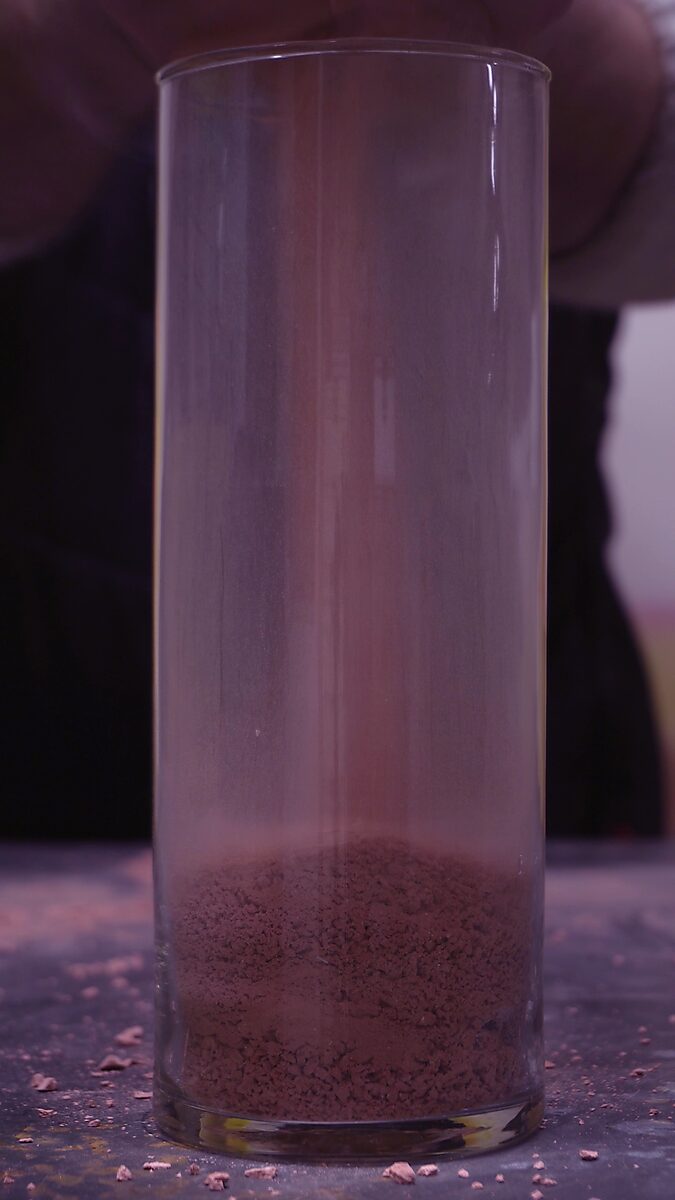 Broken Volume — videostill in which the terracotta fragments have been ground into fine dust at the bottom of the glass cylinder.