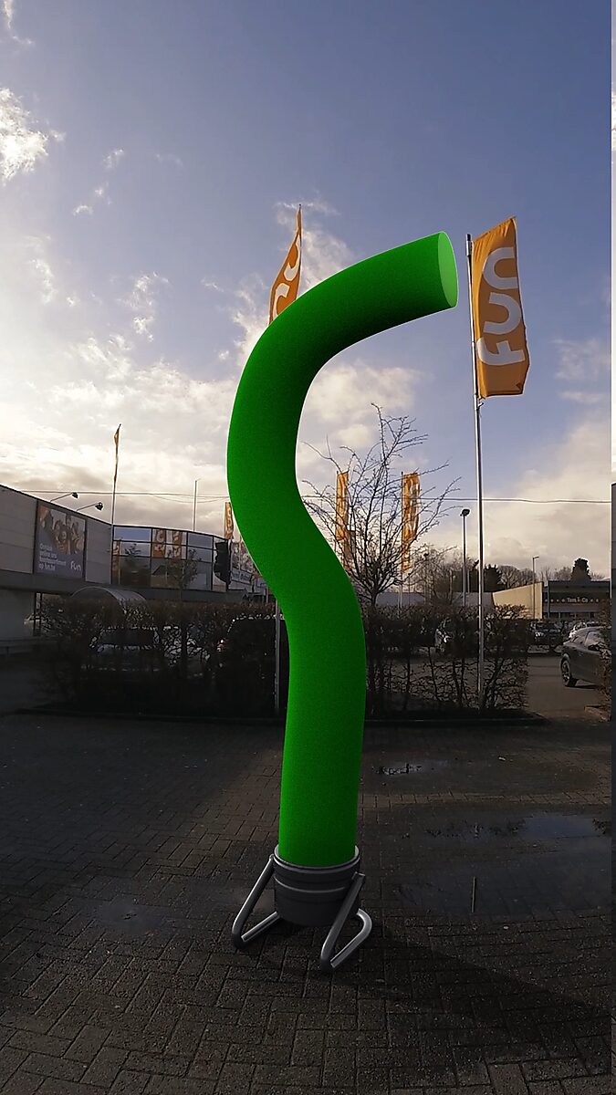 Verzet van een skytube — videostill waarin de skytube een S-vormige buiging maakt terwijl de vlaggen op de achtergrond sterke wind suggereren.