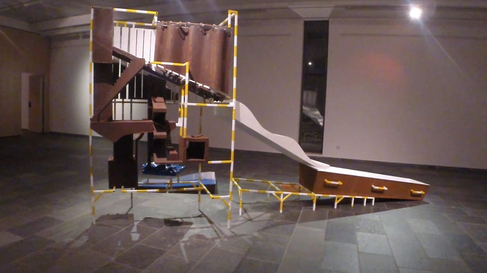 Constructie met blauw — videostill van een lineaire installatie die begint bij een bassin met ruw water, waar de constructie het startpunt van een symbolische levensloop markeert.