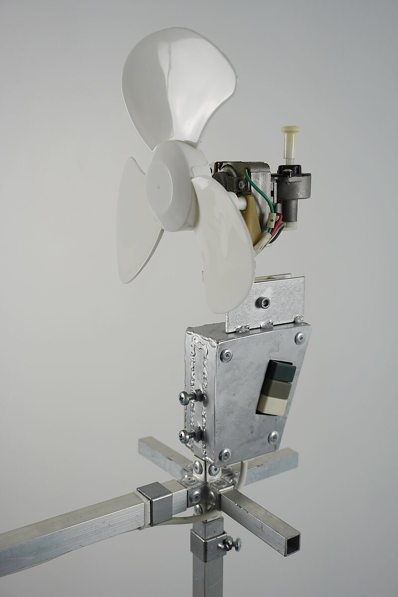 Thermiekbelofte — detail van een ventilator gemonteerd op het aluminium constructiesysteem, functionerend als mechanische bron van luchtstroom die beweging en thermische energie in de installatie introduceert.