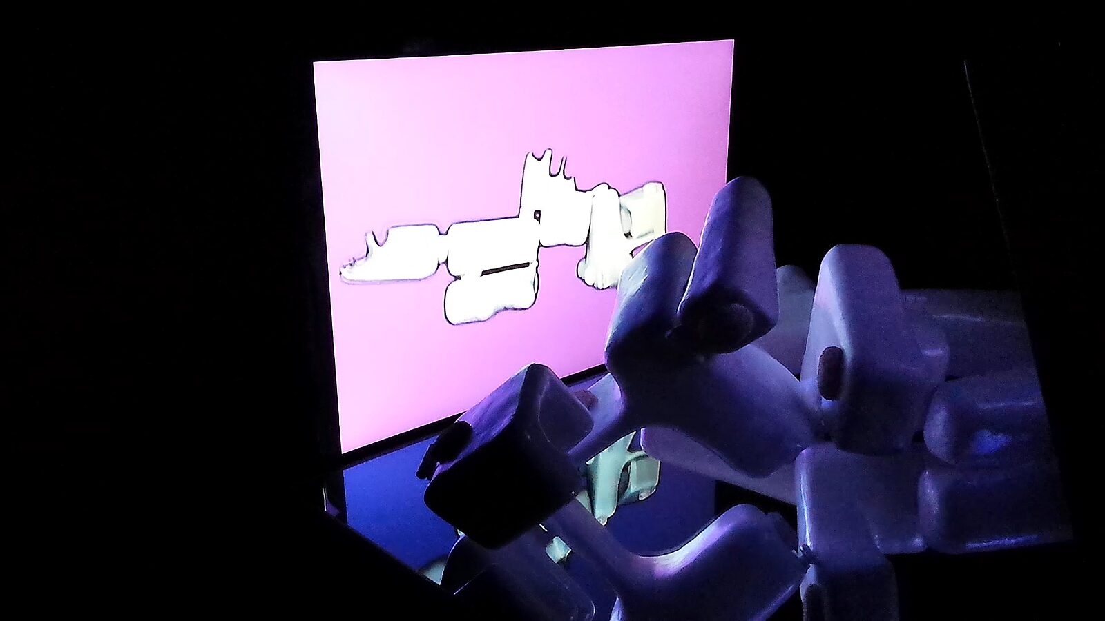 Reflections in Motion — videostill recording: a white abstract sculpture lies on a glossy surface in front of a pink screen, showing a distorted projection of the form.