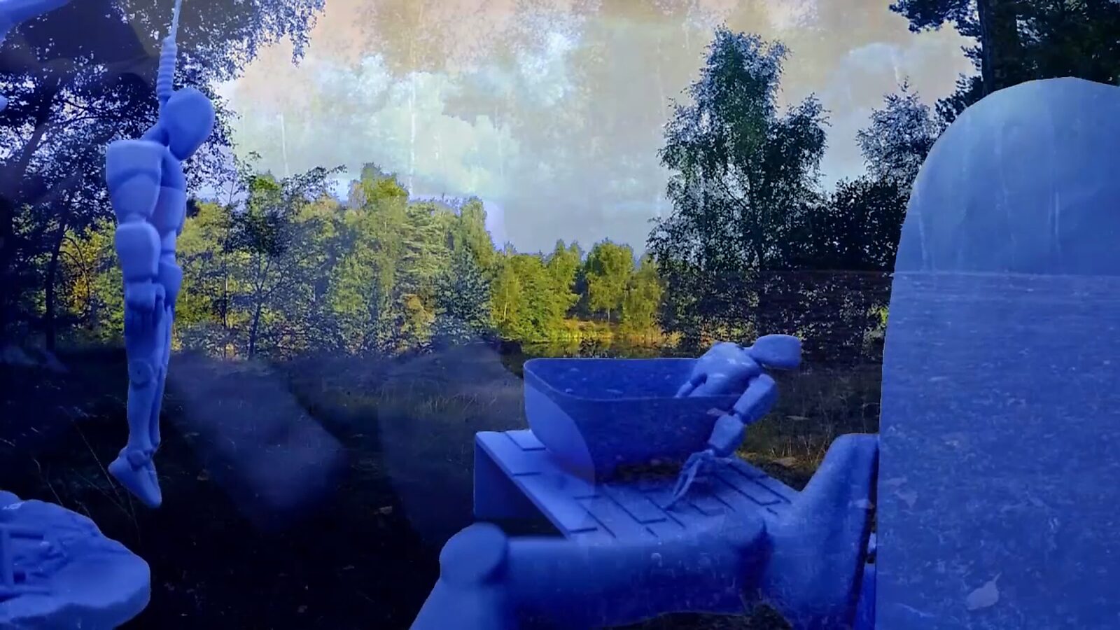 Imaginary Landscapes — video still in which a robot figure appears within a real forest landscape combined with translucent digital elements, allowing physical reality and virtual presence to merge.