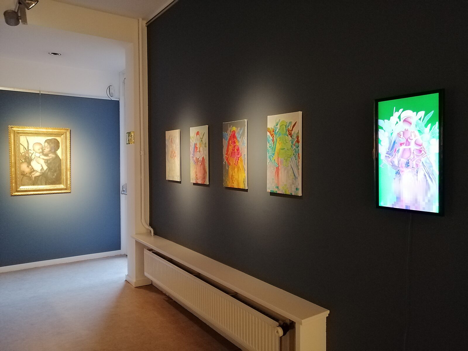 ‘Oog in Oog’: Exhibition view with a series of colourful figurative works and a lightbox on a dark wall; in the adjacent room a classical painting of mother and child by Jakob Smits in a gilded frame, Jakob Smits Museum, Mol, 2019