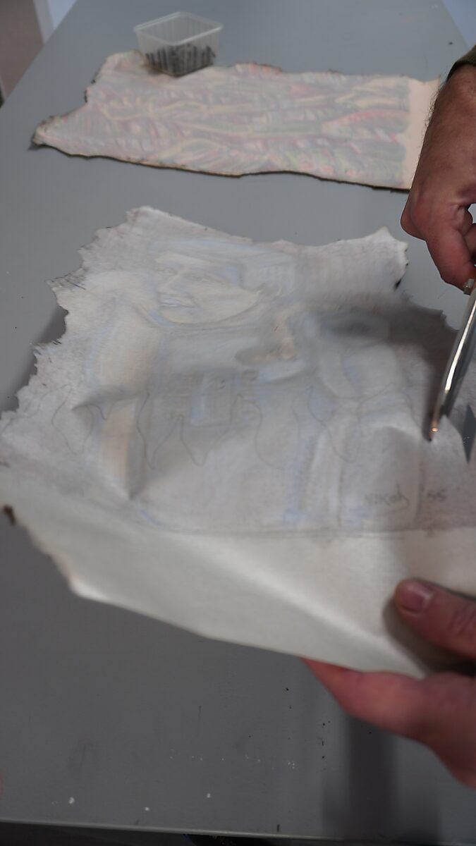 Naming–Value Butterflies — process drawing: Robotman (1995) — hands cut a piece from the burned paper with scissors while another fragment lies on the table.