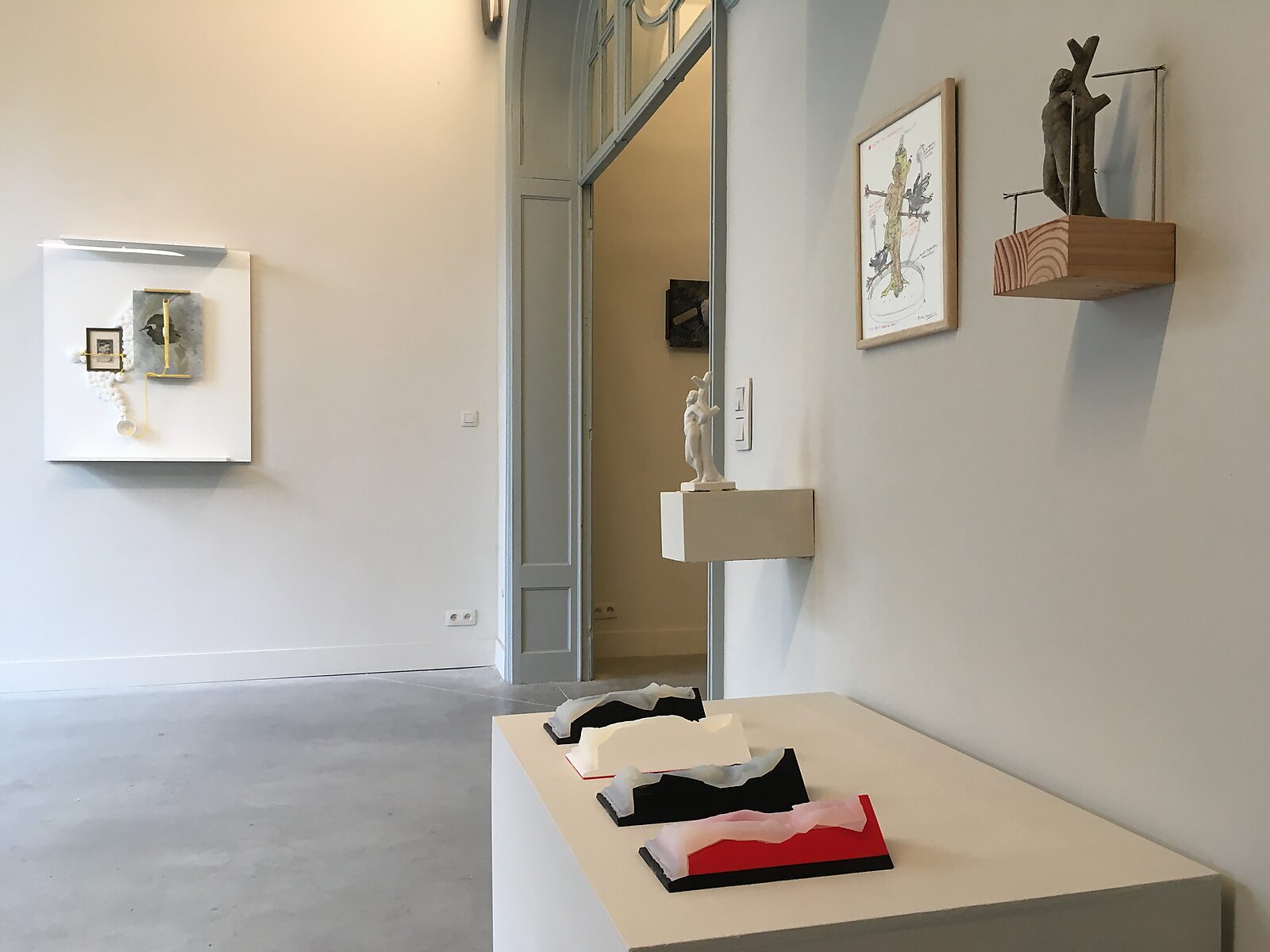 ‘I know why the caged bird sings: ’Tentoonstellingszicht met de mal in vier delen op een sokkel (transparante siliconen vormen); wandobject links en kleine sculptuur op zwevende plank bij deuropening, St. Sebatiaan, WARP, Sint-Niklaas, 2022
