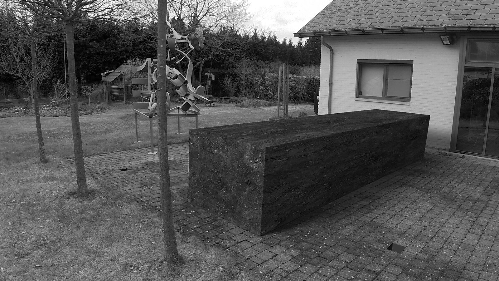 The Paver — videostill in which the paving stone appears greatly enlarged on the terrace, occupying most of the space.