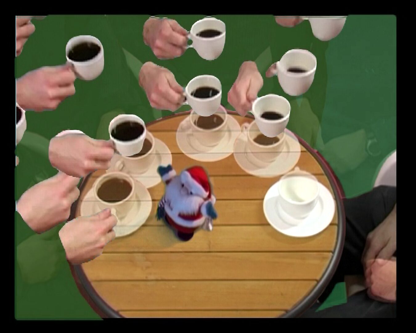 Beweging en verstilling — Een kopje koffie drinken in 180° — videostill waarin meerdere koffiekopjes boven de tafel verschijnen terwijl de kerstman opnieuw rechtop in het midden staat.