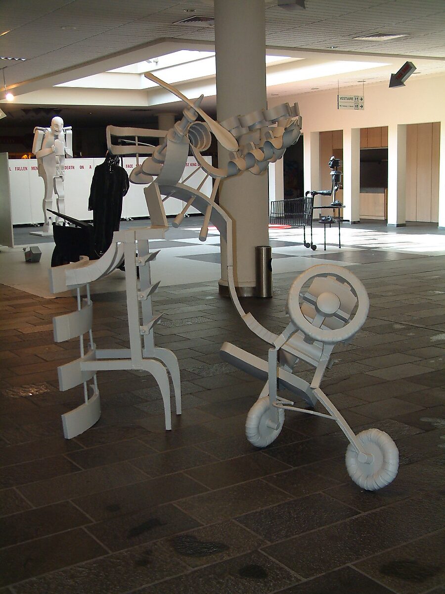 ‘Ode to Saturn’: Exhibition view with white and black metal sculptures in welded steel plate; complex white construction in the foreground and monumental figures in the space, CC De Adelberg, Lommel, 2003.