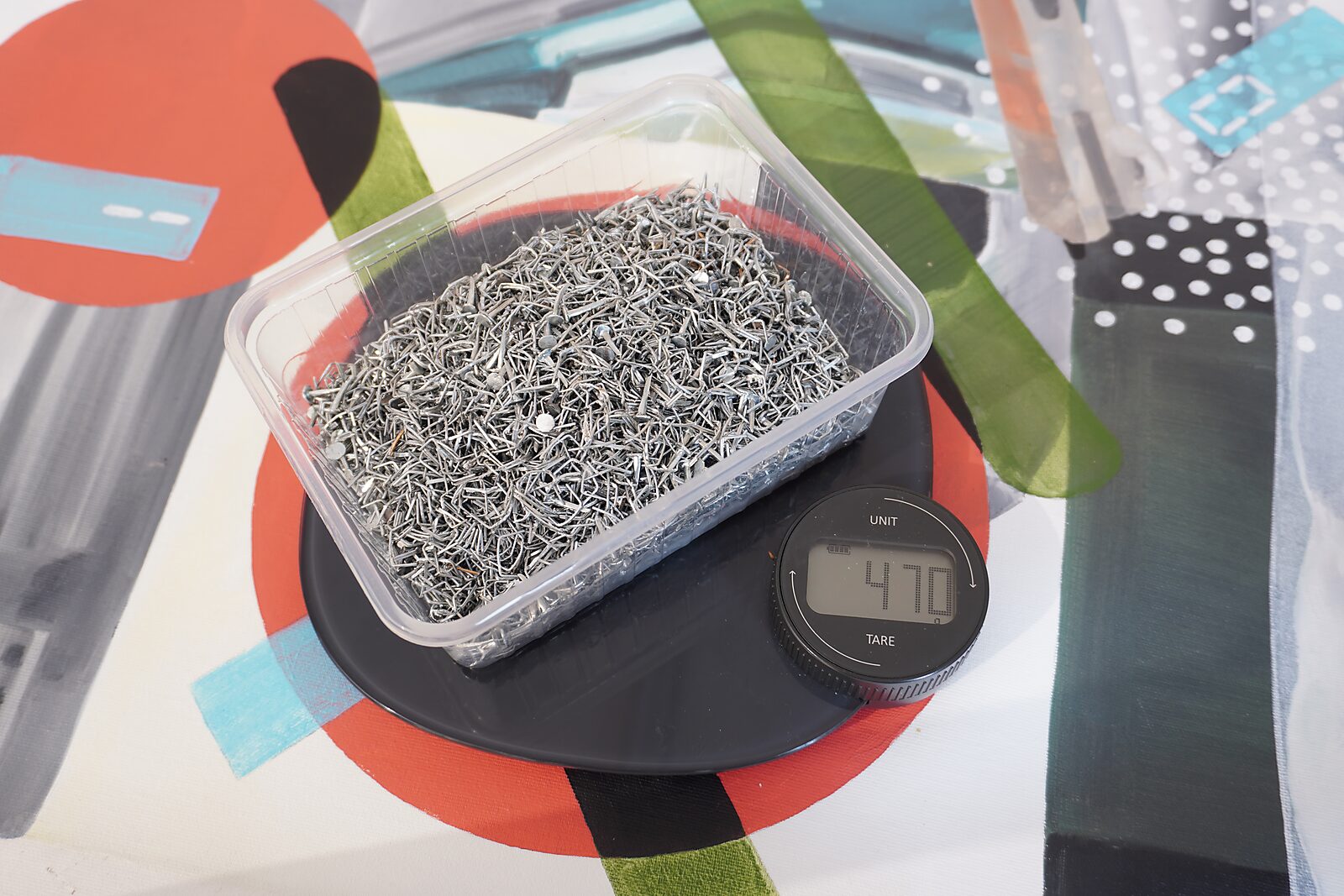 Paintings to Pure Canvas — detail showing a container filled with removed staples (total weight 470 grams), residual material from dismantling the paintings, turning fastening elements into measurable traces of transformation.