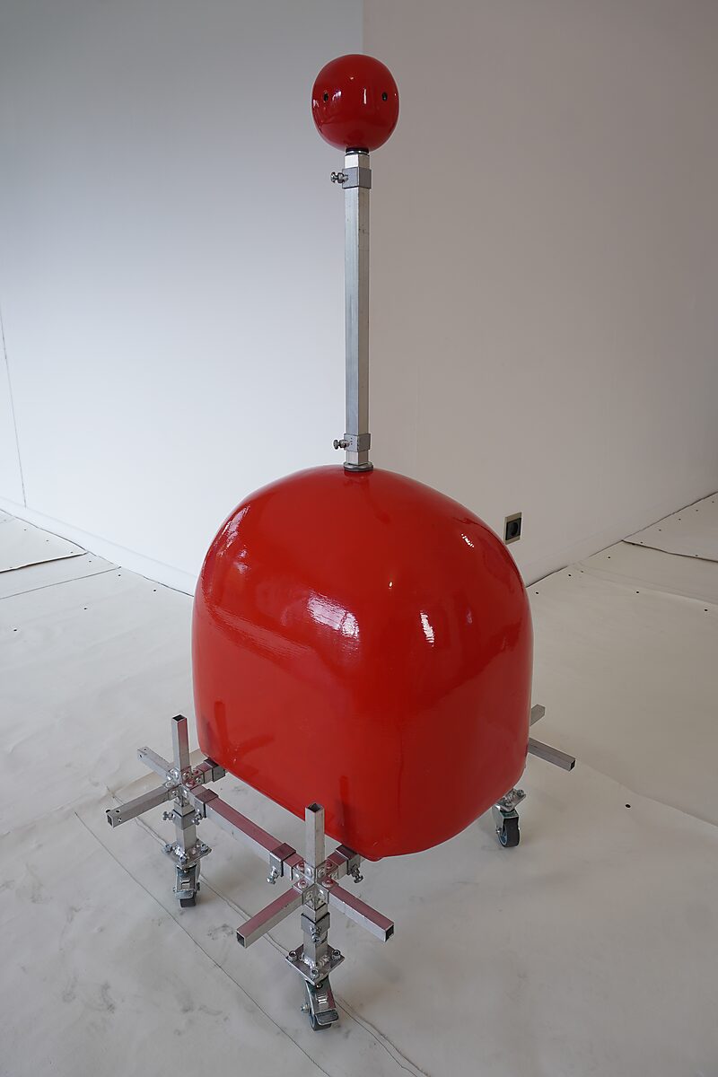 Choose and Change — studio setup with a red polyester form mounted on a mobile aluminium frame, with a vertical rod and sphere on top.