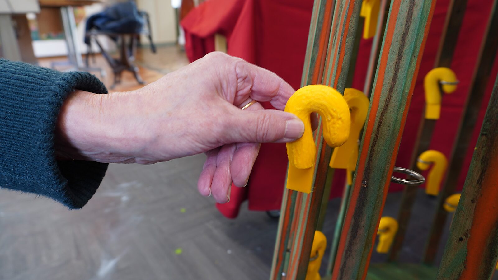 Sfincterman No.0.0 — action videostill: a larger yellow element is held and brought toward a metal ring, ready to be attached.