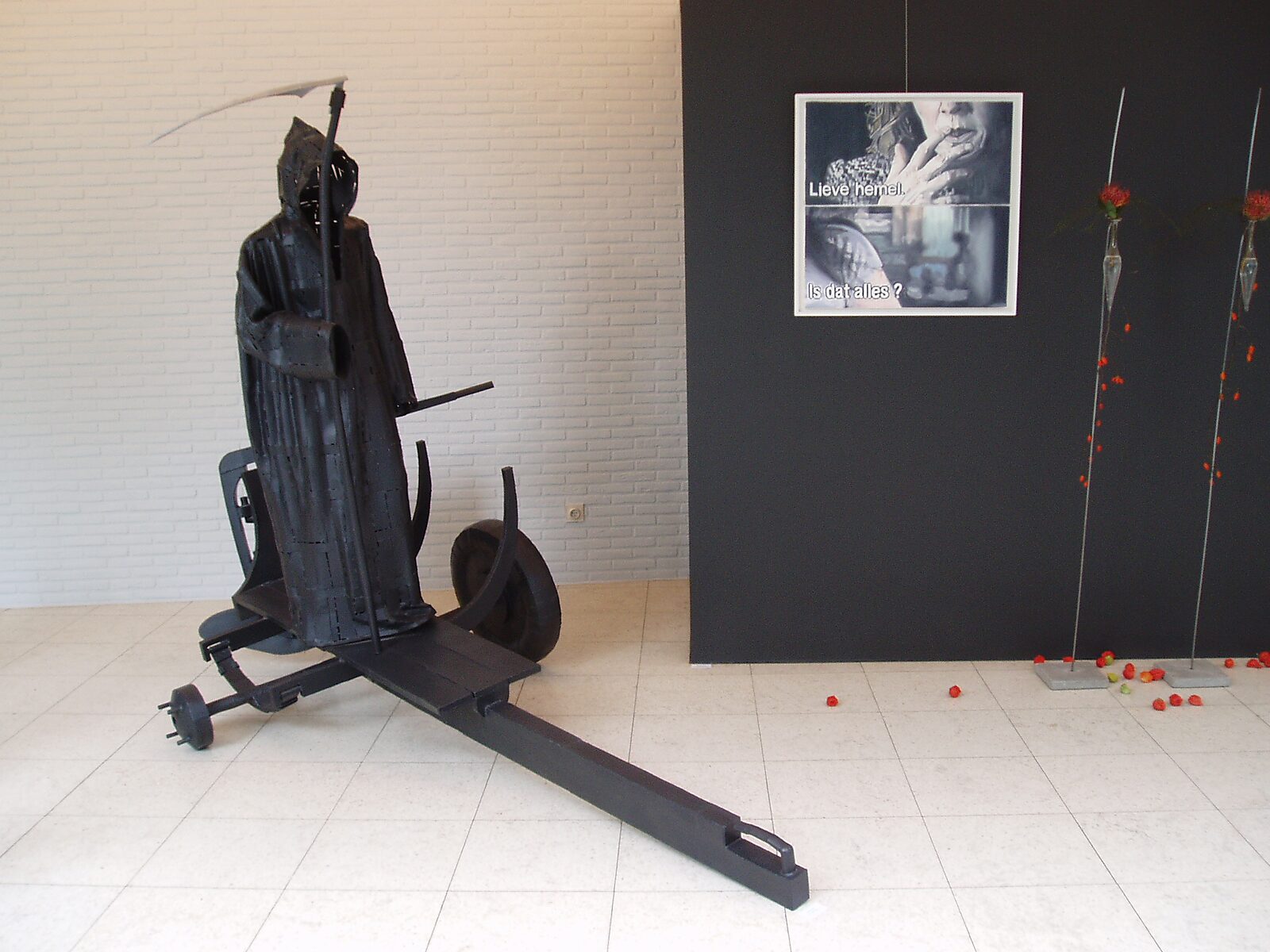 Interrupted Crossing — black metal sculpture of the ferryman installed in an exhibition space at Dommelhof Neerpelt, positioned beside a wall-mounted painting.
