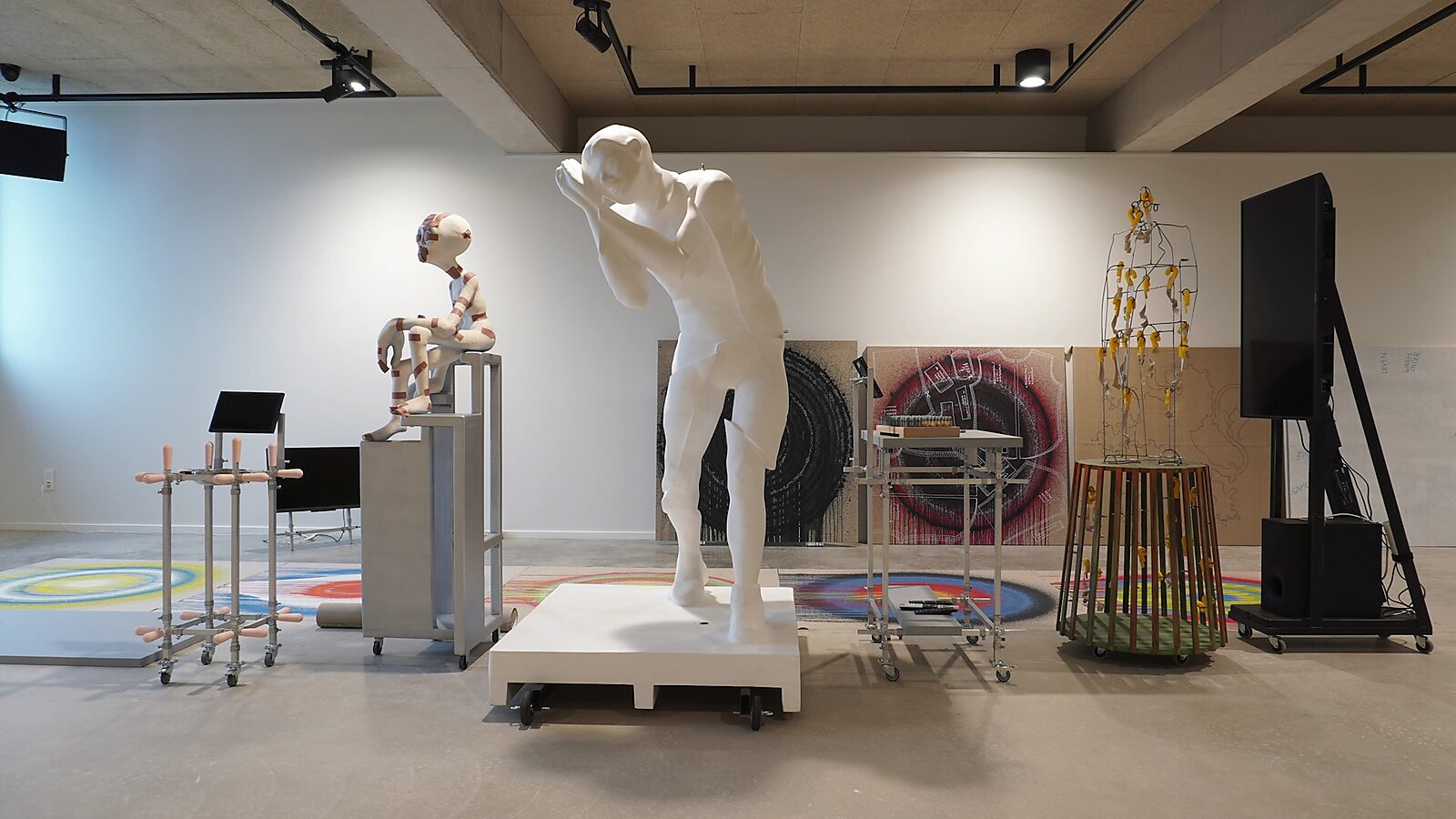 Transformatiestudio nr.1: warm of koud: Tentoonstellingszicht met witte sculptuur van een slapende man en doeken dicht bij elkaar, CC De Adelberg, Lommel, 2024.