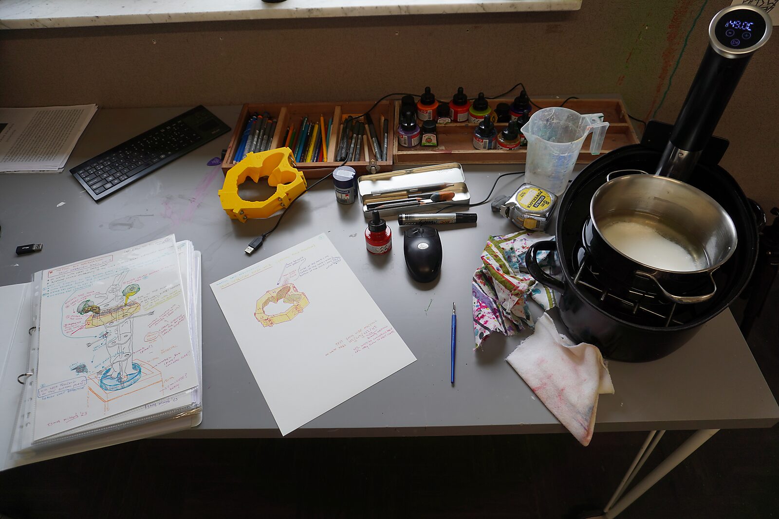 St. Sebastian with Birds No. 2 — studio photo of the worktable with sketches, tools, pigments and a heated pot used for preparing the casting mixture.