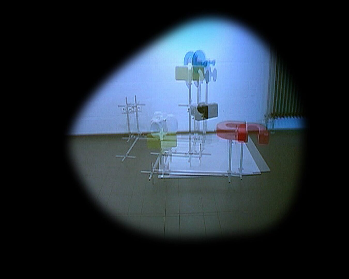 Choose and Change, Moving Installation — video still: repeated and shifted images of the installation with colored shapes, visible as overlapping motion within a circular frame.