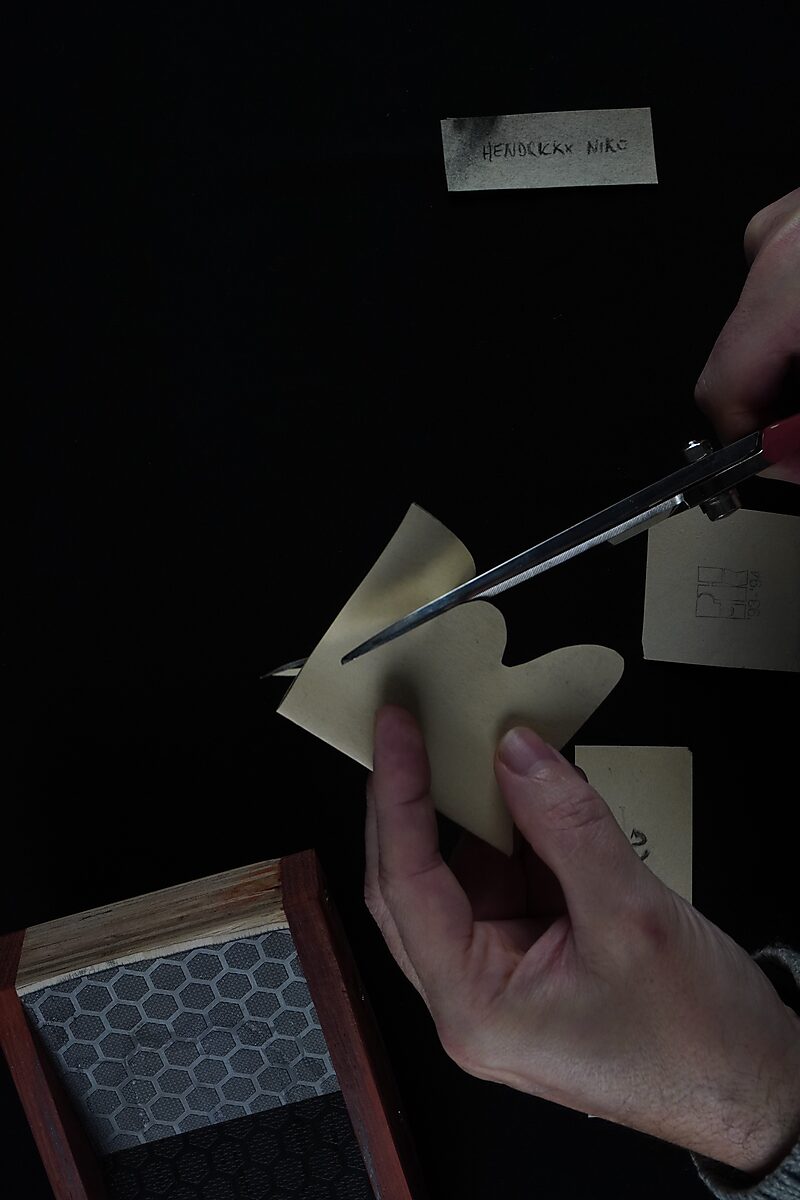 Naming–Value Butterflies — process drawing: self-portrait study 3 PHIKO (1993) — hands cut a butterfly shape from a piece of paper above an open box.