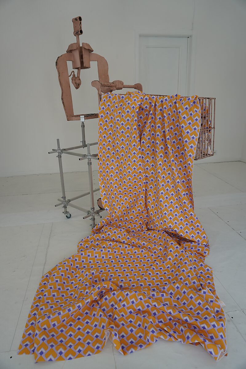 Vintage Cyborg Shopping Cart (1960 model) sculpture installed with geometric 1960s-style patterned fabric flowing from the shopping cart onto the floor.