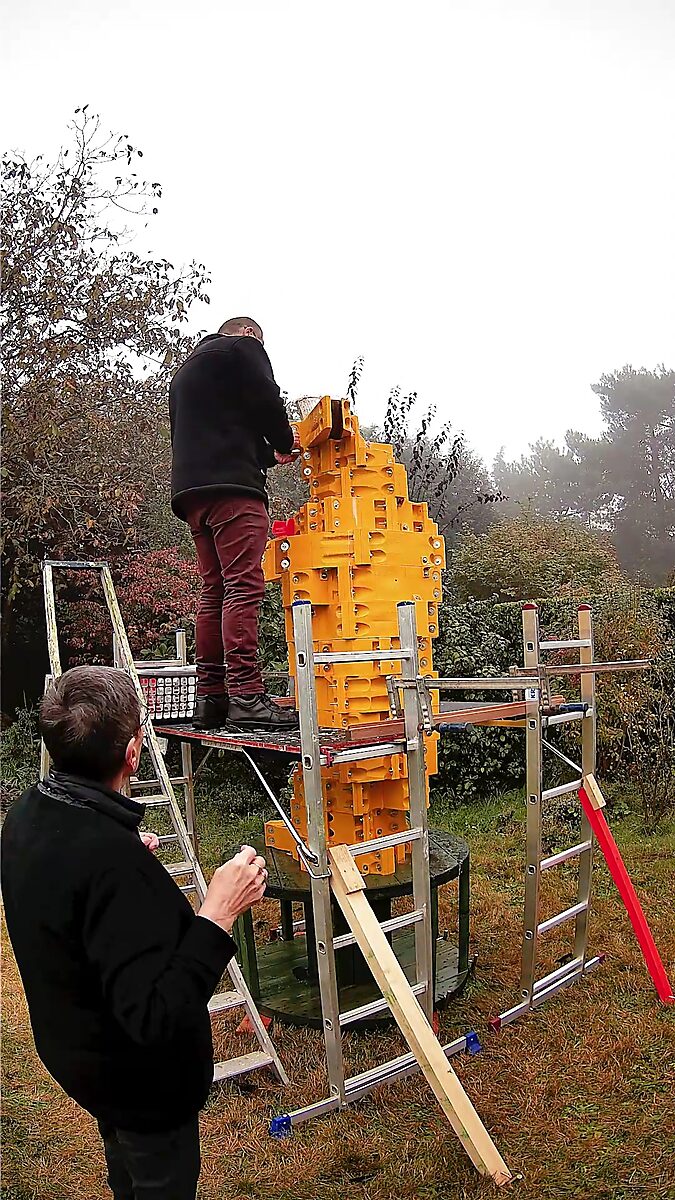 St. Sebastian with Birds No. 3 — video still showing a life-sized yellow modular mould around the figure on a raised platform, while two people work on the mould at the top.