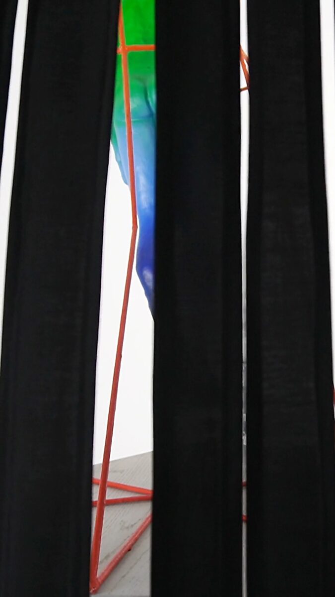 Thermal Promise — detail view of moving black fabric strips partially revealing the Mindcaging sculpture behind them, filtering perception through movement and material.