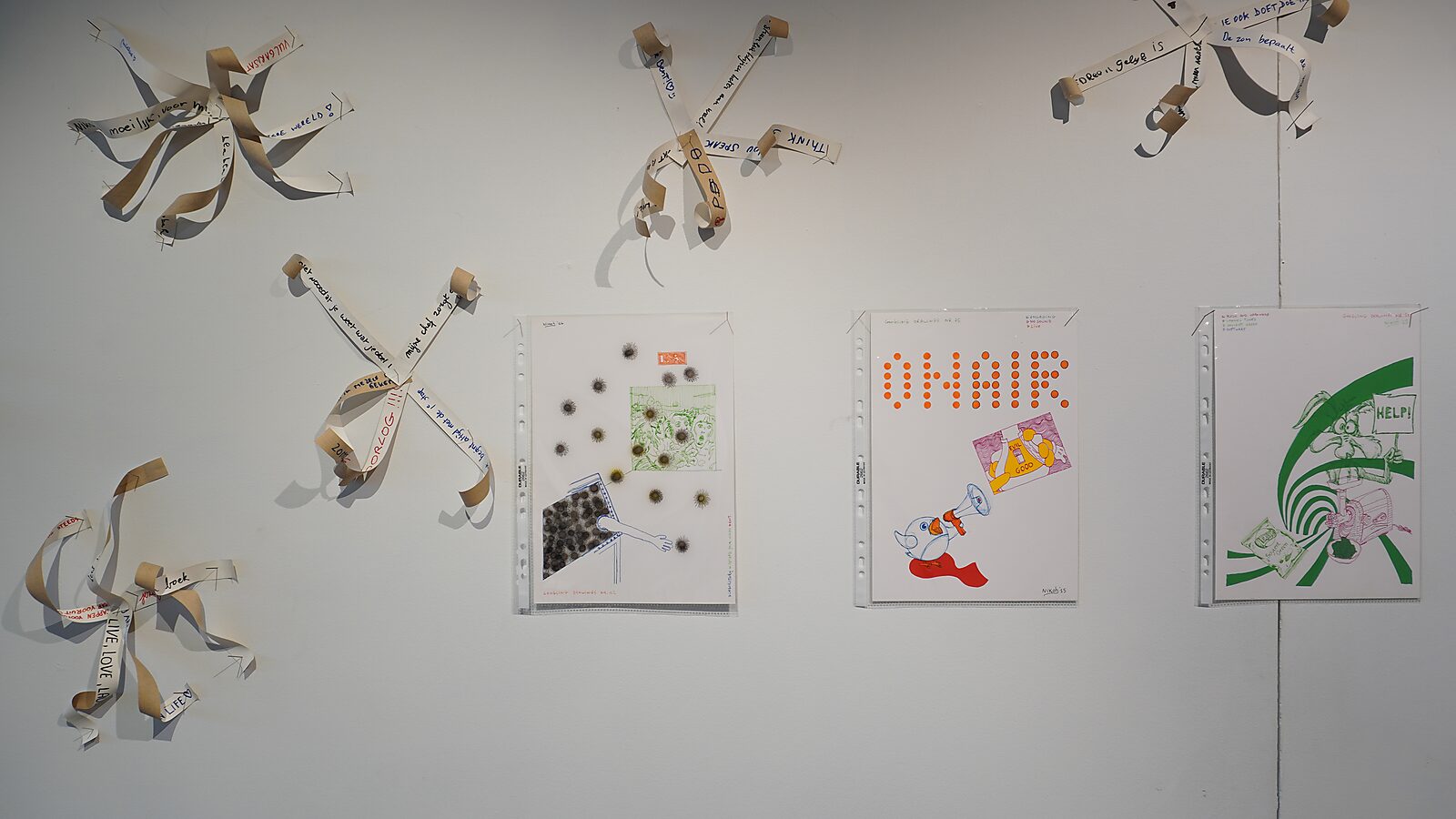 Exhibition view — Transformation Studio no.1: warm or cold, CC De Adelberg (2024) — wall installation with paper ribbons containing text fragments and framed Google drawings.