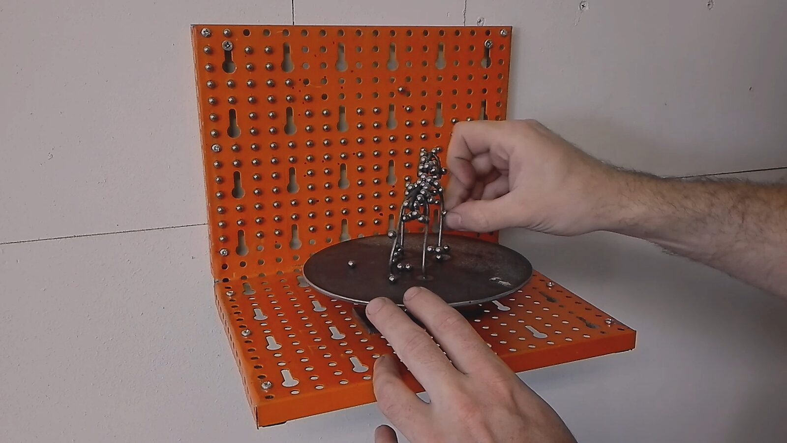 The Turning Dog — video stills: dog form made of wire and metal balls; hands manipulating the structure on a rotating metal plate.
