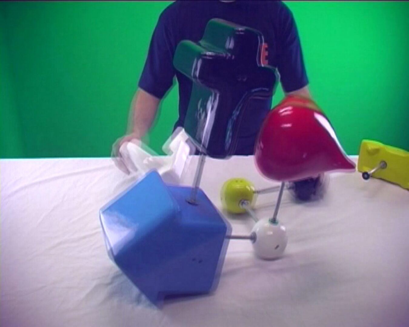 Choose and Change no. 1 — video still of a demonstration in which a person rearranges various colorful forms with metal rods on a table.