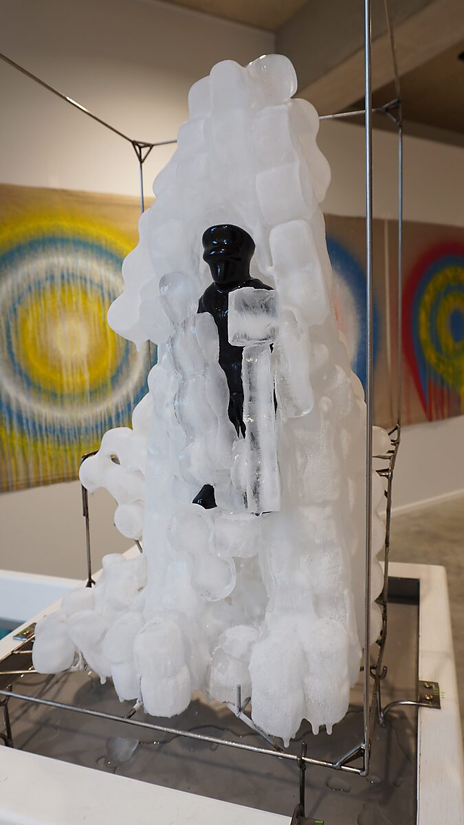 Entropische sculptuur nr. 2 — Transformatiestudio nr. 1: warm of koud, zwart polyester figuurtje gedeeltelijk omhuld door nieuw gevormd ijs.
