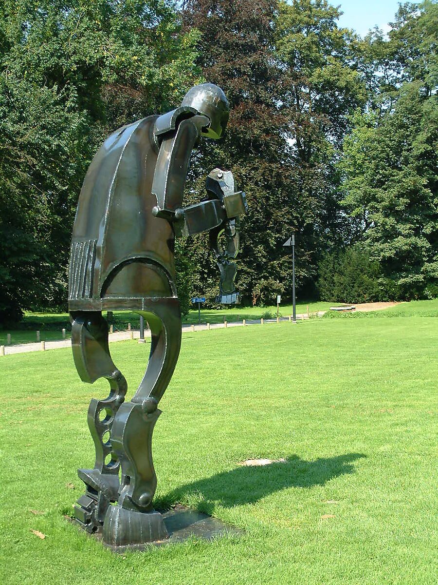 Dark varnished version of sculpture Saturn installed in park landscape at Domain Kasteel van Rullingen in Borgloon.