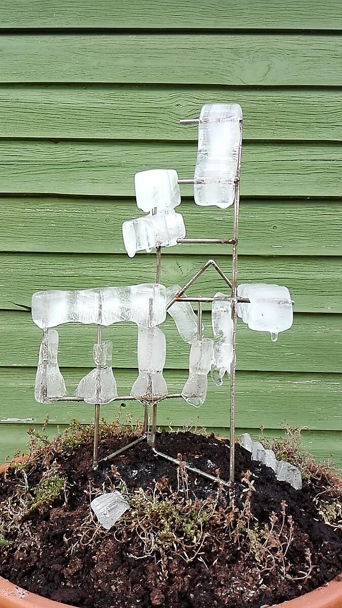 Entropische sculptuur nr. 1 — videostill waarin het ijs in de zomer verder is gesmolten en de transparante vormen dun en vervormd rond het metalen frame hangen.
