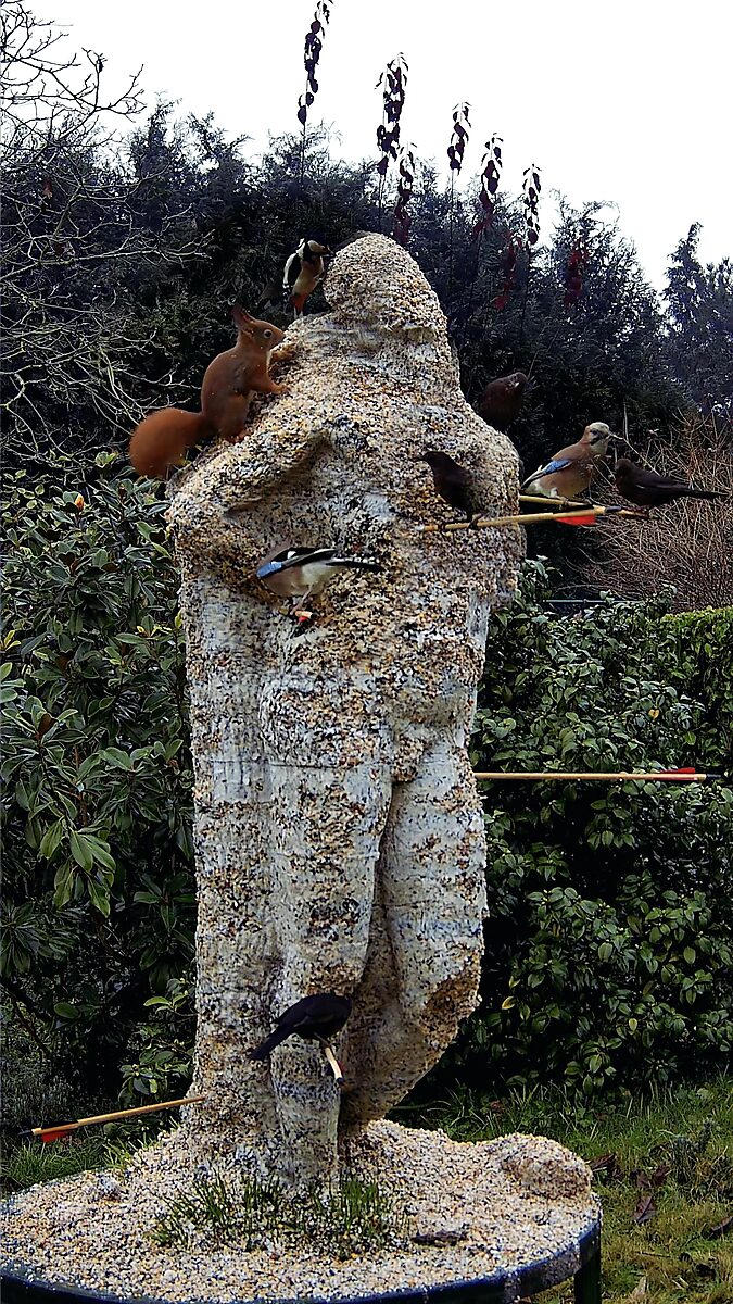 St. Sebastian with Birds No. 3 — video still in which birds and a squirrel gather around the sculpture and eat the birdseed from its surface.