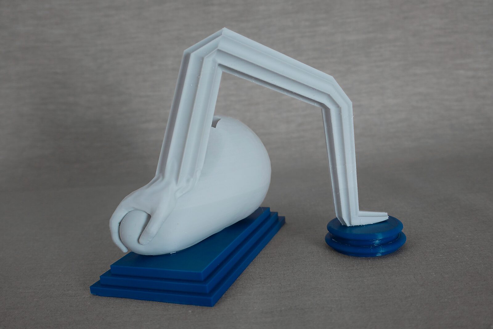The Columns of Ovidius — Arachne — side view of a 3D-printed reclining figure with a bent column form appearing detached from the body, on a blue pedestal.