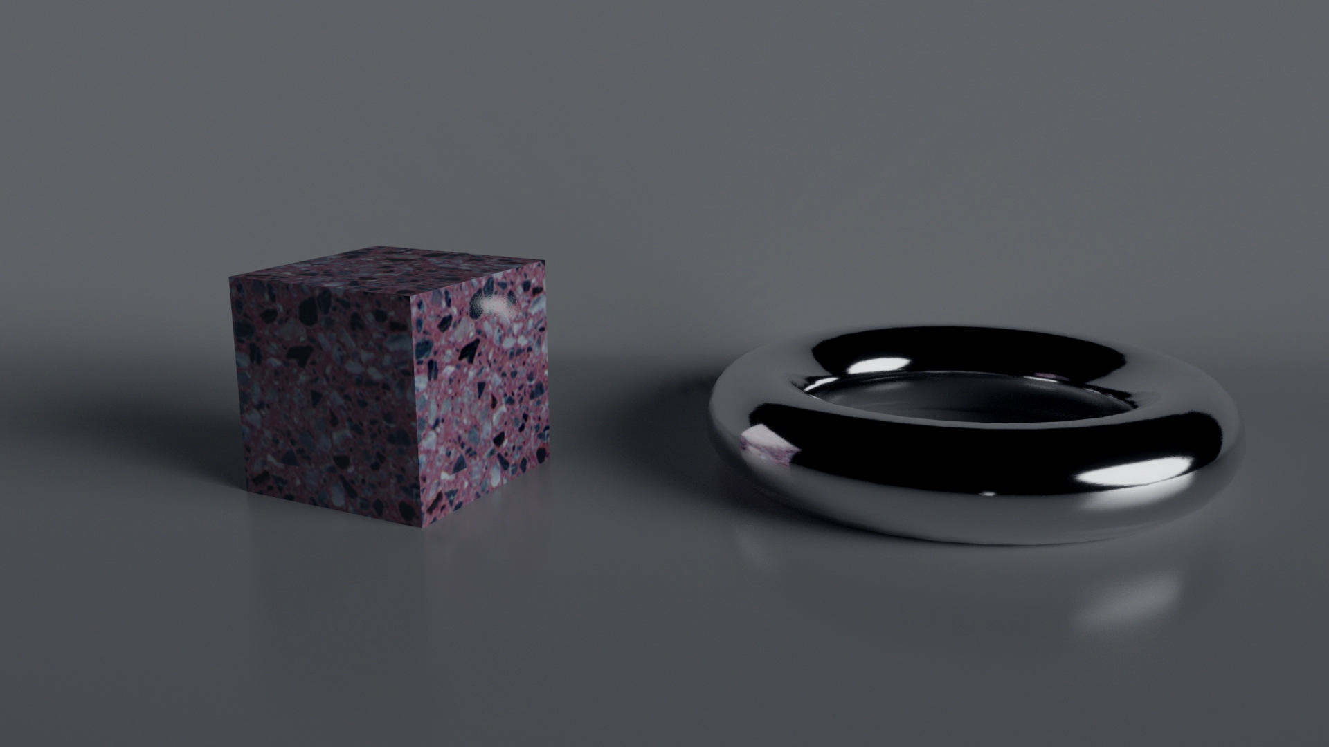 De ander willen zijn — videostill uit een 3D-animatie met links een kubus in terrazzo-structuur en rechts een gladde metalen ringvorm op een neutrale achtergrond.